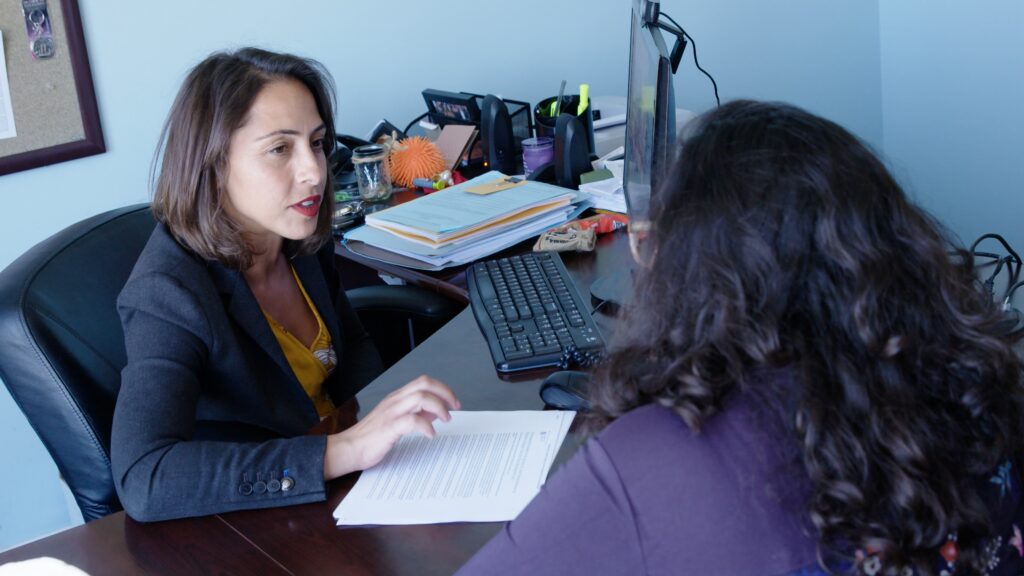 Woman sitting at a desk talking to another woman